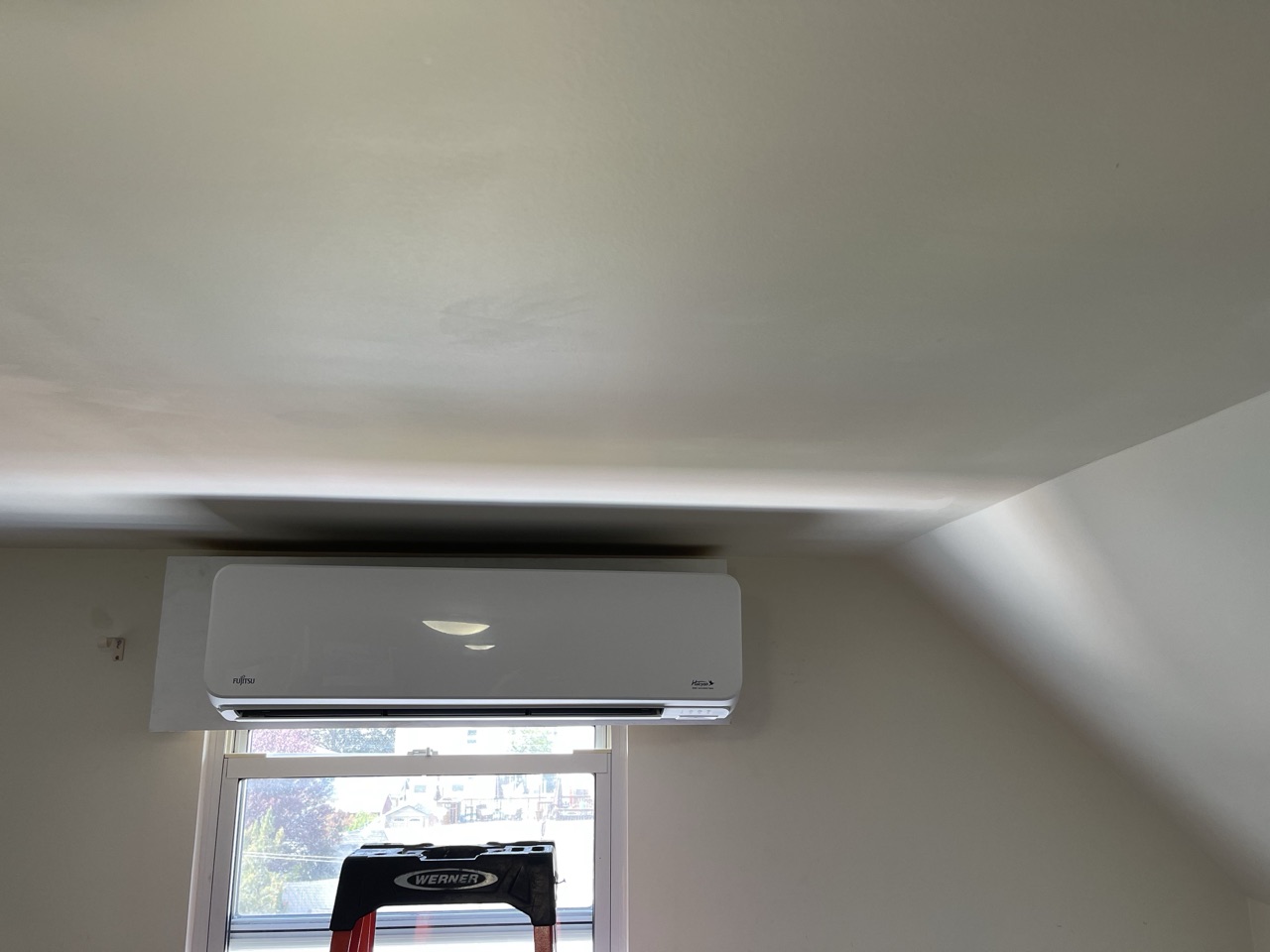 Fujitsu wall-mounted mini-split installed near a vaulted ceiling above a window in a Brooklyn home