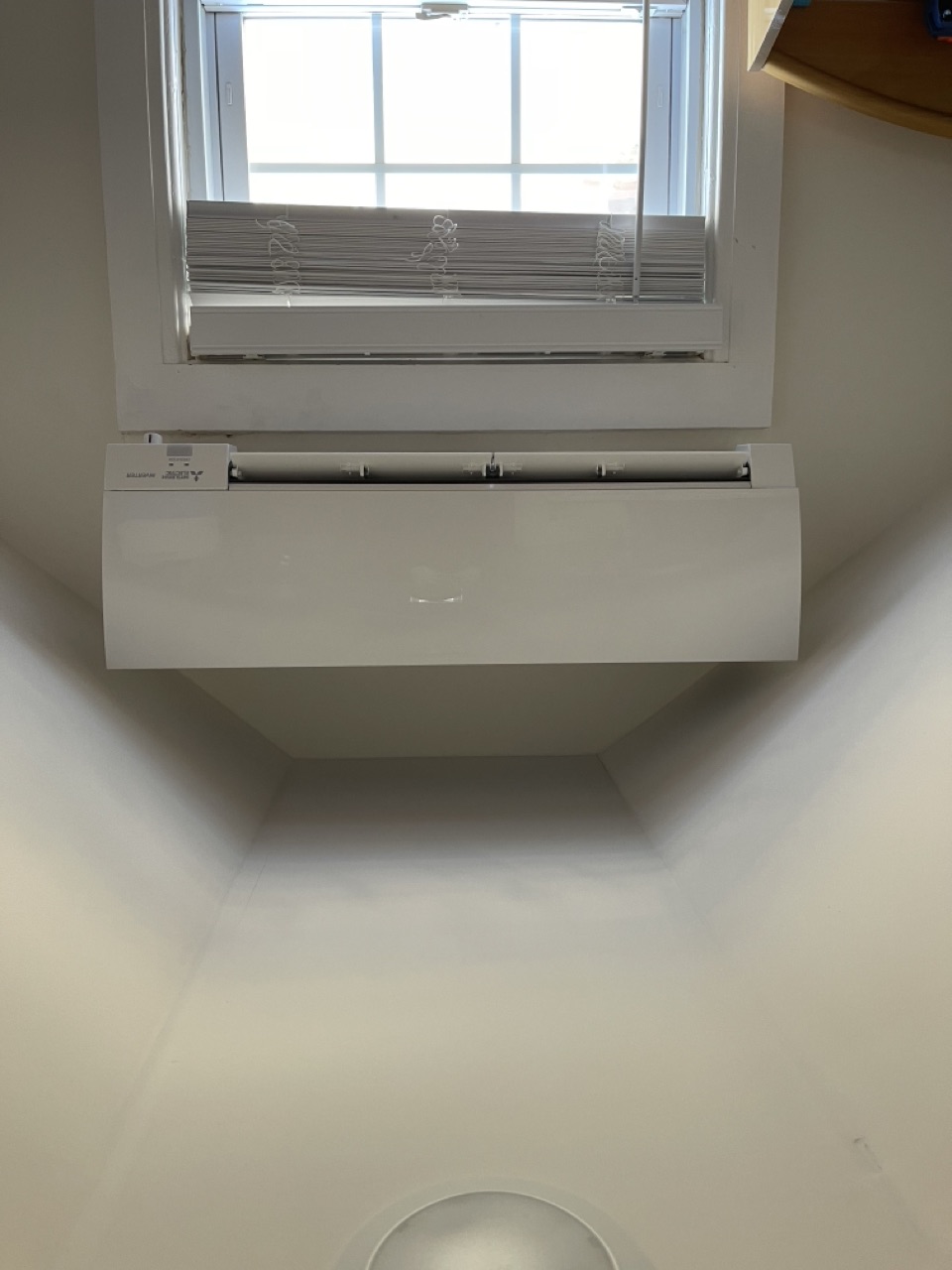 Mitsubishi Electric wall-mounted mini-split installed under a window in a sloped-ceiling attic bedroom
