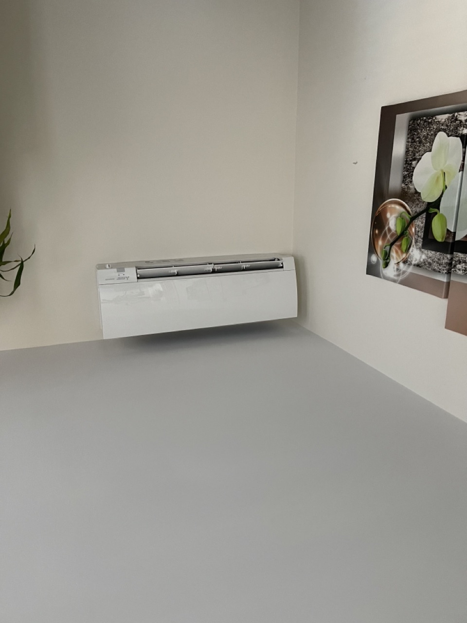 Mitsubishi Electric wall-mounted mini-split installed in the corner of a residential room next to a framed picture