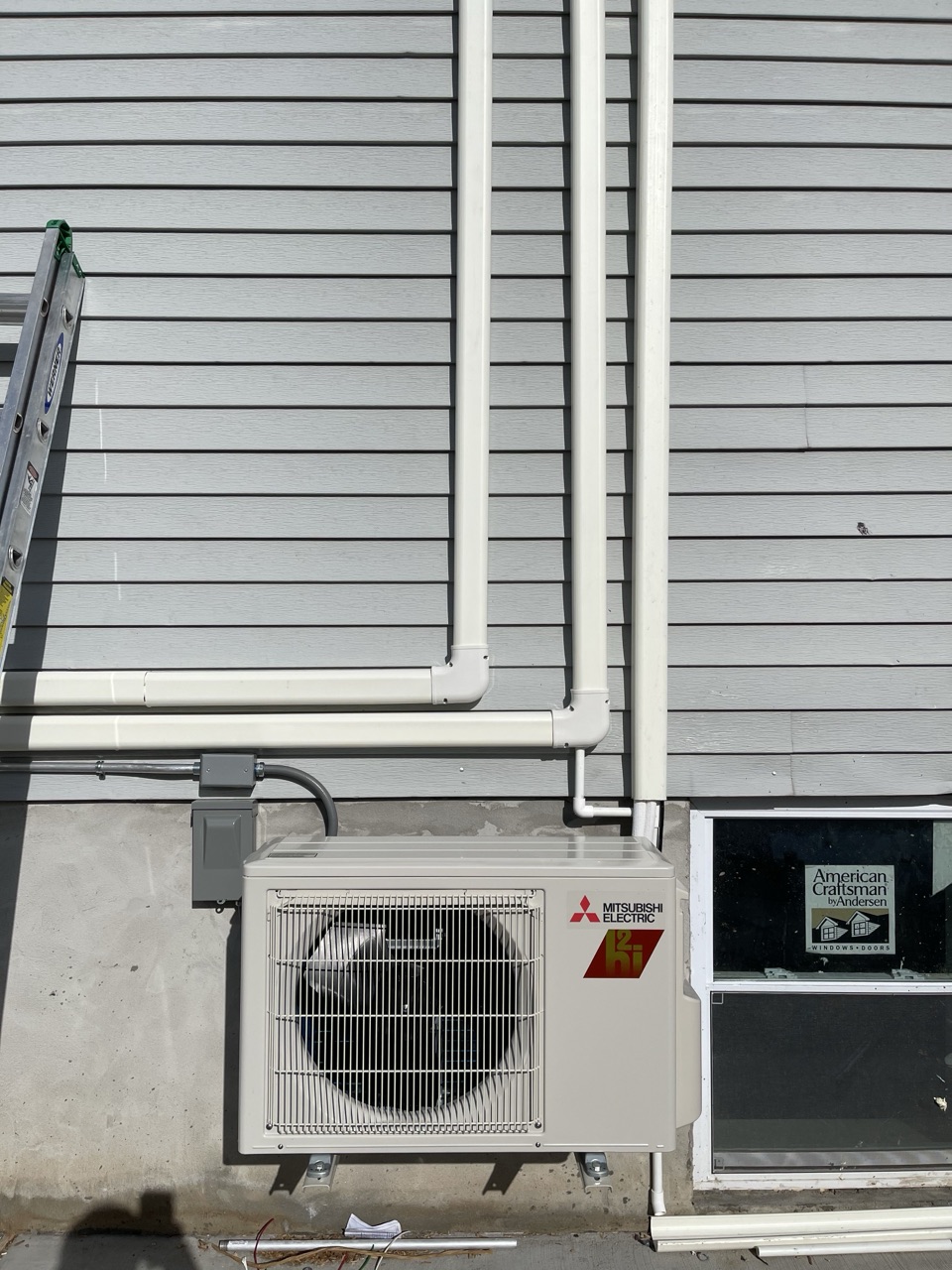 Mitsubishi Electric Mr.Slim outdoor condenser unit installed on a gray-sided Brooklyn home wall with neat insulated line sets