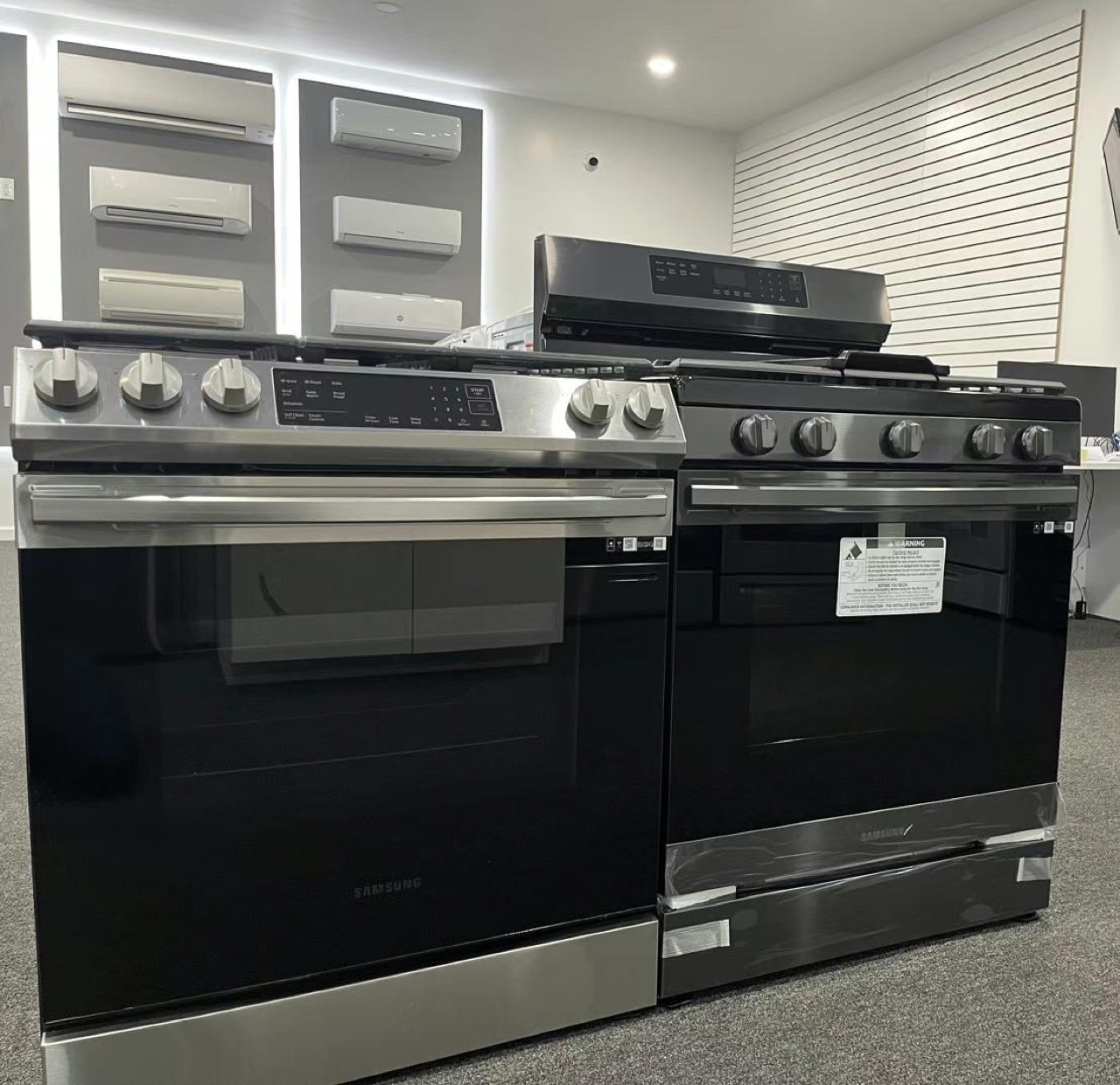 Samsung electric and gas ranges on display next to Mitsubishi mini-split heads inside the Kings AC Supply Brooklyn showroom