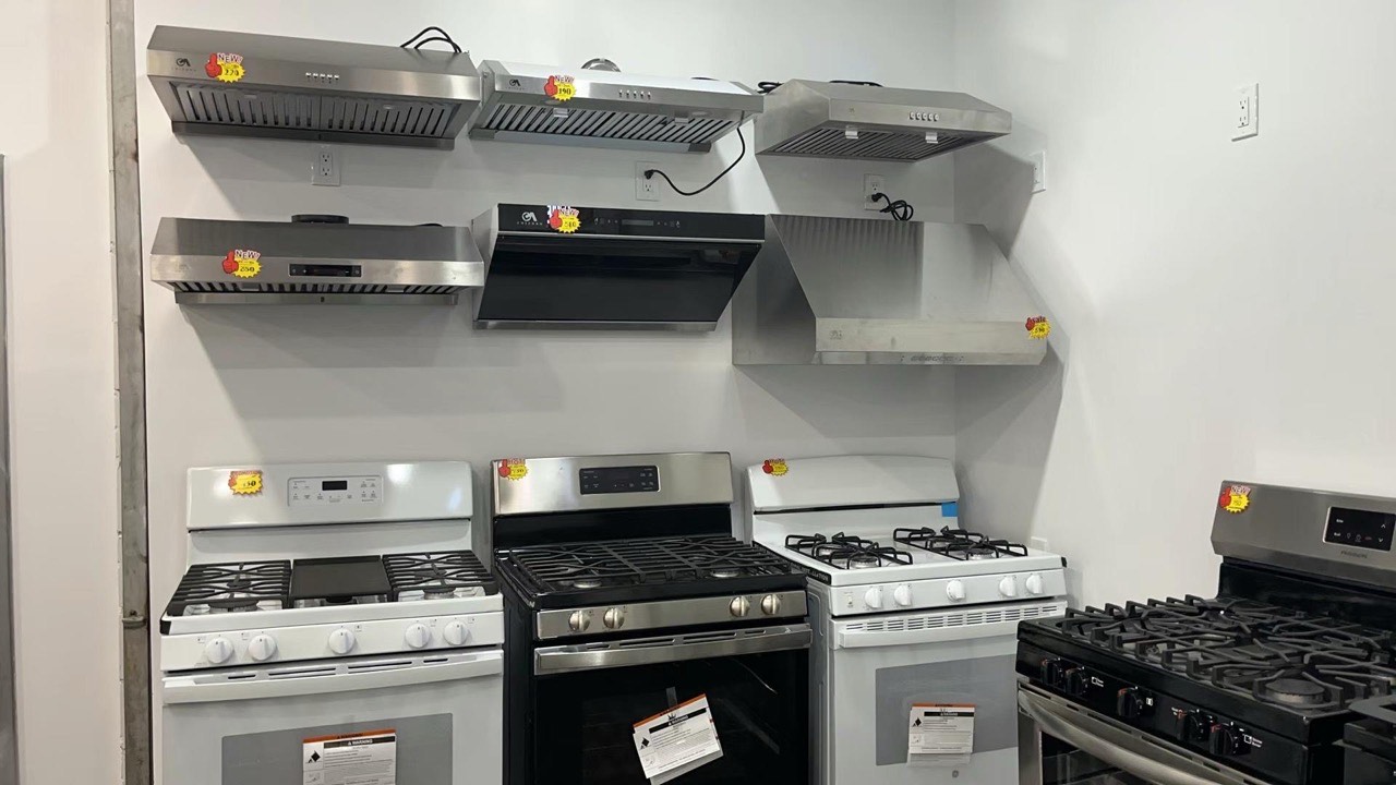 Stainless-steel range hoods and gas stoves on display in the Kings AC Supply Brooklyn showroom with sale tags