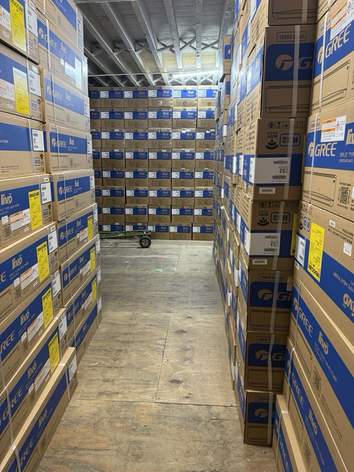 Long warehouse aisle lined with Gree split-system AC unit boxes