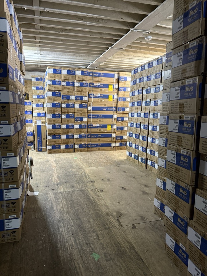 Floor-to-ceiling stacks of Gree and Livo AC boxes in wholesale storage
